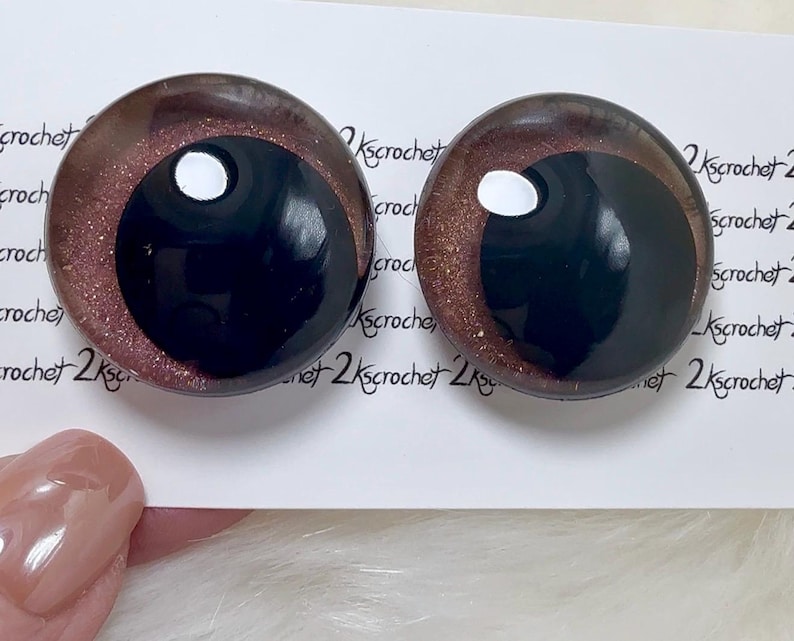 May include: Two round, black and brown glass eyes with a white pupil. The eyes have a glittery, shimmery finish.