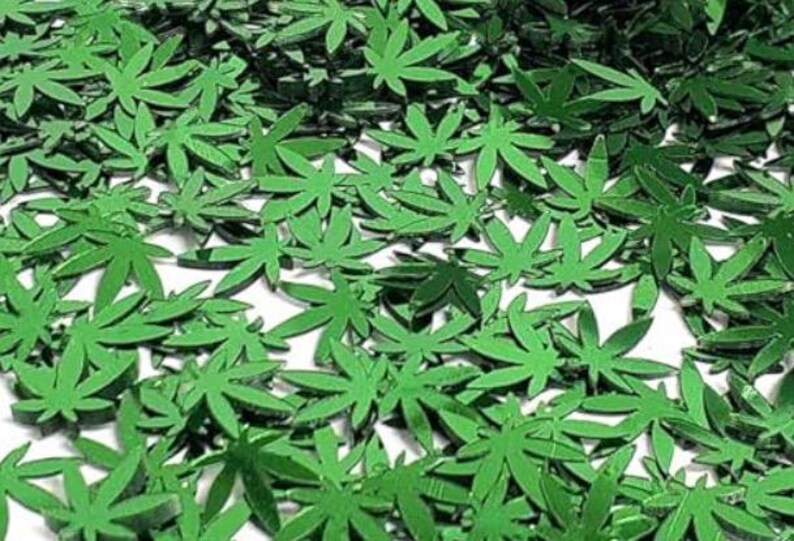 Peut inclure: Une collection de petites d&eacute;coupes en forme de feuilles de cannabis vert vif. Les feuilles sont dispers&eacute;es sur une surface blanche, cr&eacute;ant un motif dense et textur&eacute;. Les feuilles ont une finition brillante et sont de couleur uniforme.
