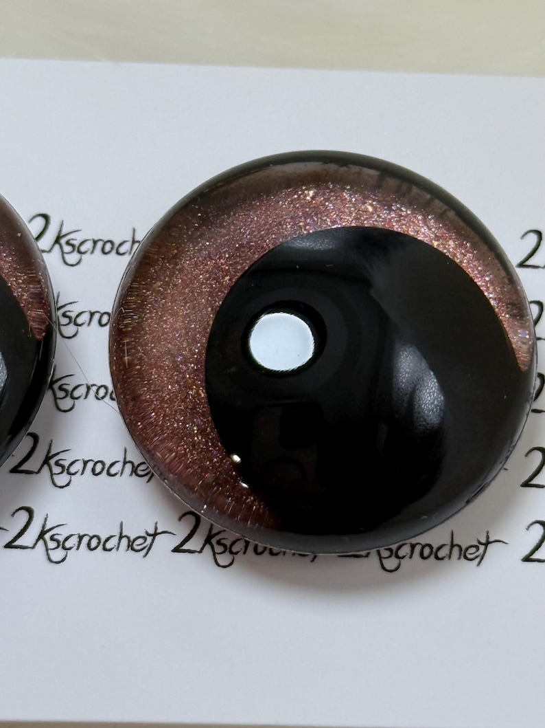 May include: A pair of black and brown glass eyes with a glitter finish. The eyes have a white pupil and a black iris.