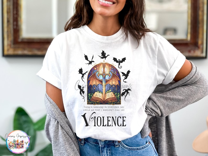 May include: White t-shirt featuring a fantasy-themed graphic. The design includes a sword, open book, dragons, and the word "VIOLENCE". The shirt also has the text "THERE'S NOWHERE IN EXISTENCE YOU COULD GO THAT I WOULDN'T FIND YOU".