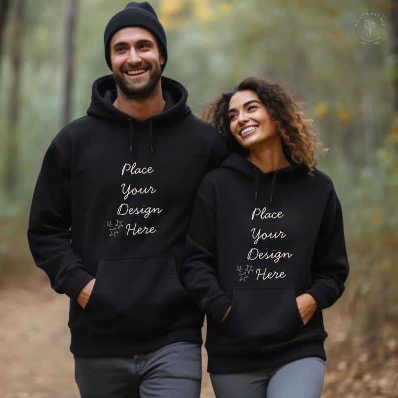 Pode incluir: Duas pessoas vestindo moletons pretos com o texto "Place Your Design Here". Os moletons t&ecirc;m um bolso frontal e um capuz com cord&atilde;o. Uma pessoa est&aacute; usando um gorro preto. O fundo &eacute; uma cena externa desfocada.