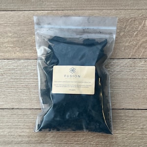 Może przedstawiać: Przezroczysty plastikowy worek wypełniony czarnymi kawałkami węgla drzewnego. Worek ma etykietę z napisem "Fusion Charcoal Wood" i "Charcoal-Activated Carbon from 100% American White Oak". Etykieta zawiera również napis "Stosowany do filtrowania spirytusu z olejów opałowych i innych niechcianych zanieczyszczeń, aby spirytus był jak najbardziej gładki." oraz "100 gramów".