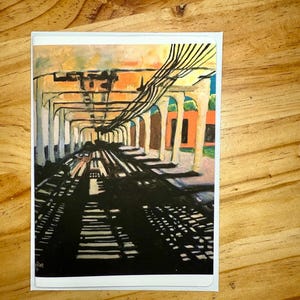 Puede incluir: Una impresi&oacute;n art&iacute;stica del interior de una estaci&oacute;n de tren, con una vista en perspectiva de las v&iacute;as y los soportes arqueados. La obra de arte utiliza una paleta de naranja, marr&oacute;n y negro, con un enfoque en las sombras y la luz. La impresi&oacute;n est&aacute; en una tarjeta blanca.