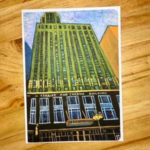 Puede incluir: Una colorida impresi&oacute;n art&iacute;stica del edificio Carbide and Carbon. El edificio est&aacute; representado en tonos verdes, azules y amarillos, con las palabras "CARBIDE AND CARBON BUILDING" en la parte superior. La obra de arte est&aacute; firmada "AR 23".