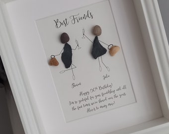 Peut inclure: Une œuvre d'art encadrée représentant deux personnages en pierre, avec le texte "Best Friends" en haut. Les personnages tiennent des verres et des sacs, et le texte ci-dessous indique "Happy 50th Birthday! I'm so grateful for your friendship and all the fun times we've shared over the years. Here's to many more!"