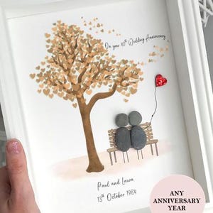 May include: Framed anniversary artwork. A tree with heart-shaped leaves, a stone couple on a bench, and a red heart balloon. Text reads "On your 40th Wedding Anniversary", and "Paul and Laura 13th October 1984".