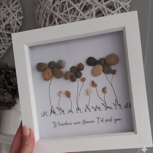 May include: White framed artwork featuring pebble flowers with thin black stems and grass. The pebbles are in shades of brown, tan, and grey. The text at the bottom reads, "If teachers were flowers, I'd pick you."