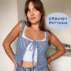 May include: A light blue crochet top with a tie closure. The top is worn over a white tank top. The image includes the text "CROCHET PATTERN" in a blue bubble.