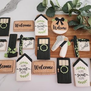 Puede incluir: Una colecci&oacute;n de 13 galletas de az&uacute;car decoradas con varios dise&ntilde;os de tem&aacute;tica de casa, incluyendo letreros de bienvenida, letreros de hogar dulce hogar, letreros de vendido y un llavero con una llave y una casa. Las galletas est&aacute;n decoradas con glaseado negro, glaseado verde y glaseado blanco.
