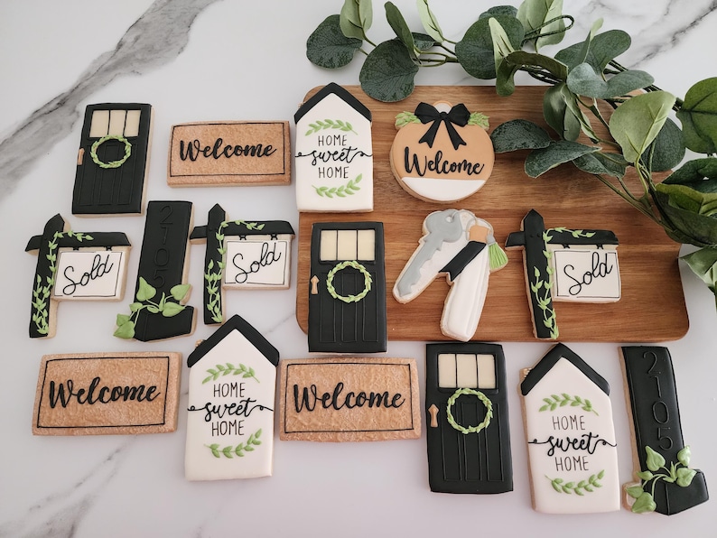 Puede incluir: Una colecci&oacute;n de 13 galletas de az&uacute;car decoradas con varios dise&ntilde;os de tem&aacute;tica de casa, incluyendo letreros de bienvenida, letreros de hogar dulce hogar, letreros de vendido y un llavero con una llave y una casa. Las galletas est&aacute;n decoradas con glaseado negro, glaseado verde y glaseado blanco.
