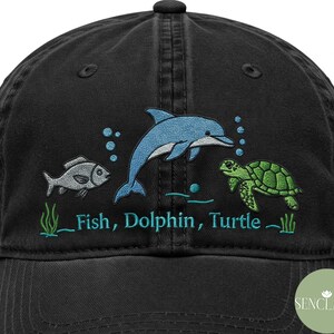 May include: Black cotton baseball cap with embroidered images of a fish, dolphin, and turtle. The text "Fish, Dolphin, Turtle" is embroidered in green below the images.