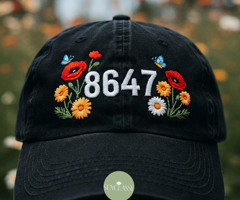 May include: Black baseball cap with embroidered red and yellow flowers, butterflies, and the number 8647.