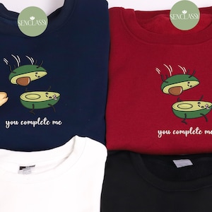 Könnte beinhalten: Zwei dunkelblaue, rote, weiße und schwarze Sweatshirts mit einer Grafik von zwei Avocadohälften mit Gesichtern und dem Text "You complete me".