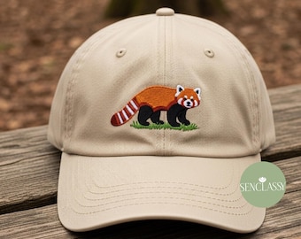 Könnte beinhalten: Beige Baseballkappe mit gesticktem Roten Panda-Design. Der Rote Panda hat einen braunen Körper, schwarze Beine und ein weißes Gesicht. Die Kappe hat einen gebogenen Schirm und einen Knopf oben.