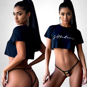 Op de afbeelding: Zwarte crop top met het woord "Suthelene" in witte letters. Het model draagt een zwarte string. De afbeelding is een studio-opname met een witte achtergrond. Het model draagt gouden oorbellen.