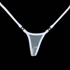 Puede incluir: Tanga de lencería blanco con un delicado panel frontal de malla y tirantes finos. Las correas están conectadas con pequeños detalles metálicos decorativos. El tanga presenta un pequeño diseño bordado en la parte delantera.