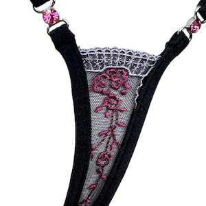 Puede incluir: Tanga negro con bordado floral rosa y delicado encaje. Tirantes ajustables con adornos de gemas rosas. Lencer&iacute;a elegante y c&oacute;moda para ocasiones especiales.