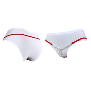 Può includere: Intimo bianco con fascia rossa e una catena di perle attaccata alla parte anteriore.