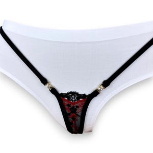 May include: Black lingerie with red lace detail and rhinestone accents. The lingerie has a white cotton base and thin black straps.