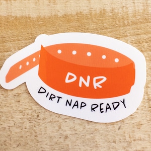 May include: Orange and white sticker with a cartoon illustration of a dog collar with the text "DNR Dirt Nap Ready".