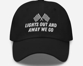Puede incluir: Gorra de béisbol negra con visera curva. La gorra presenta el texto blanco "LIGHTS OUT AND AWAY WE GO" y dos banderas a cuadros cruzadas. Un accesorio clásico e informal.