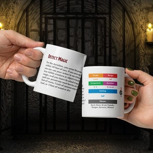 Puede incluir: Dos tazas blancas con un hechizo de Dungeons and Dragons, Detect Magic, impreso en ellas. Las tazas están sostenidas por dos manos. El texto en las tazas incluye la descripción del hechizo, los componentes, el tiempo de lanzamiento, el alcance, la duración y las clases que pueden usar el hechizo.