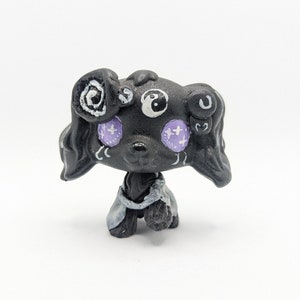 May include: Black and white custom painted figurine of a dog with purple eyes and white details. The dog is wearing a black and white robe.