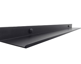 May include: Black metal shelf with a slight angle. The shelf has two visible screws on the top.