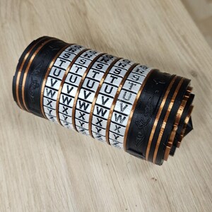Peut inclure: Un cadenas à combinaison noir et cuivre avec plusieurs anneaux rotatifs. Chaque anneau porte une lettre de l'alphabet imprimée dessus, commençant par la lettre S et se terminant par la lettre Y.