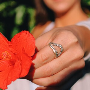 Shark Jaw Ring on a hand holding a red flower