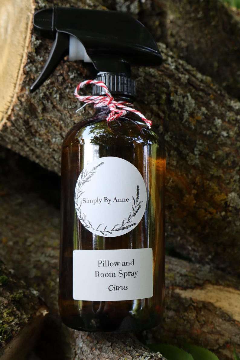 Pode incluir: Uma garrafa de vidro marrom com um bico de pulveriza&ccedil;&atilde;o preto e um r&oacute;tulo branco que diz "Simply By Anne" e "Pillow and Room Spray Citrus".