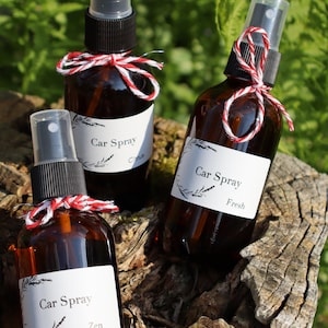 以下が含まれることがあります： スプレーノズルと白いラベルが付いた茶色のガラス瓶が3本。ラベルには「Car Spray」とあり、柑橘系、フレッシュ、禅の3種類の香りが書かれている。瓶は赤と白の紐で結ばれている。