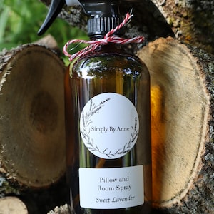 Pode incluir: Uma garrafa de vidro marrom com um bico de pulveriza&ccedil;&atilde;o preto e um r&oacute;tulo branco que diz "Simply By Anne Pillow and Room Spray Sweet Lavender".