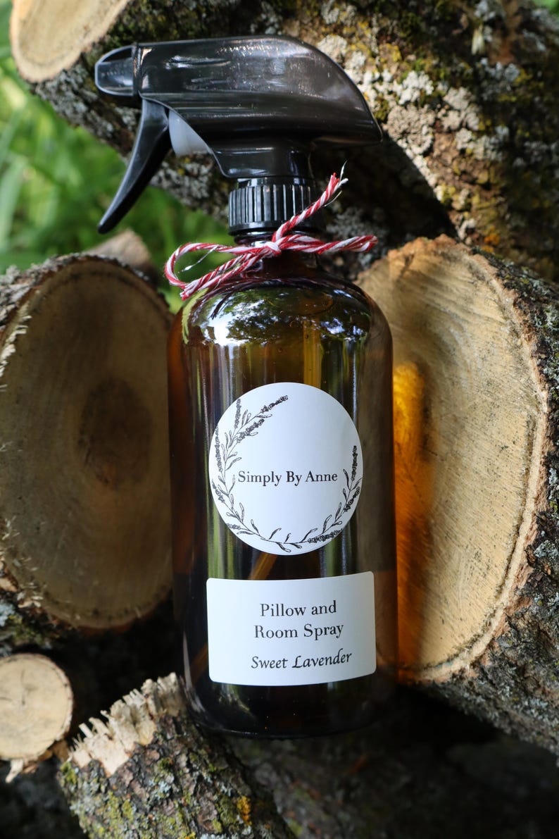 Pode incluir: Uma garrafa de vidro marrom com um bico de pulveriza&ccedil;&atilde;o preto e um r&oacute;tulo branco que diz "Simply By Anne Pillow and Room Spray Sweet Lavender".