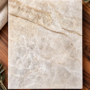 May include: A rectangular stone board featuring a polished surface with a translucent, off-white base color and prominent, swirling beige and light brown veining throughout the natural mineral pattern of the slab.