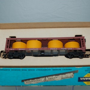 May include: A model train car in a box. The maroon car has four yellow cylindrical tanks and the words "H.J. HEINZ COMPANY PICKLE TANK CAR 73". The box is blue and has the Athearn Trains logo.