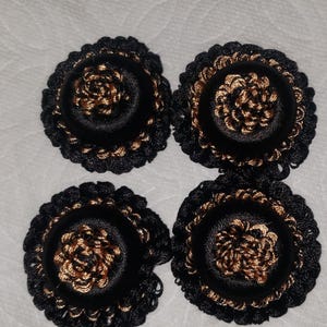 Peut inclure: Quatre ornements décoratifs noirs et dorés. Chaque pièce circulaire présente un bord extérieur noir avec un centre doré. Le centre a un motif en spirale. Ceux-ci pourraient être utilisés pour des projets d'artisanat ou de couture.