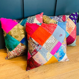 May include: Three colourful patchwork cushions featuring a mix of fabrics and patterns. The cushions are made from upcycled materials and have a unique, bohemian style.
