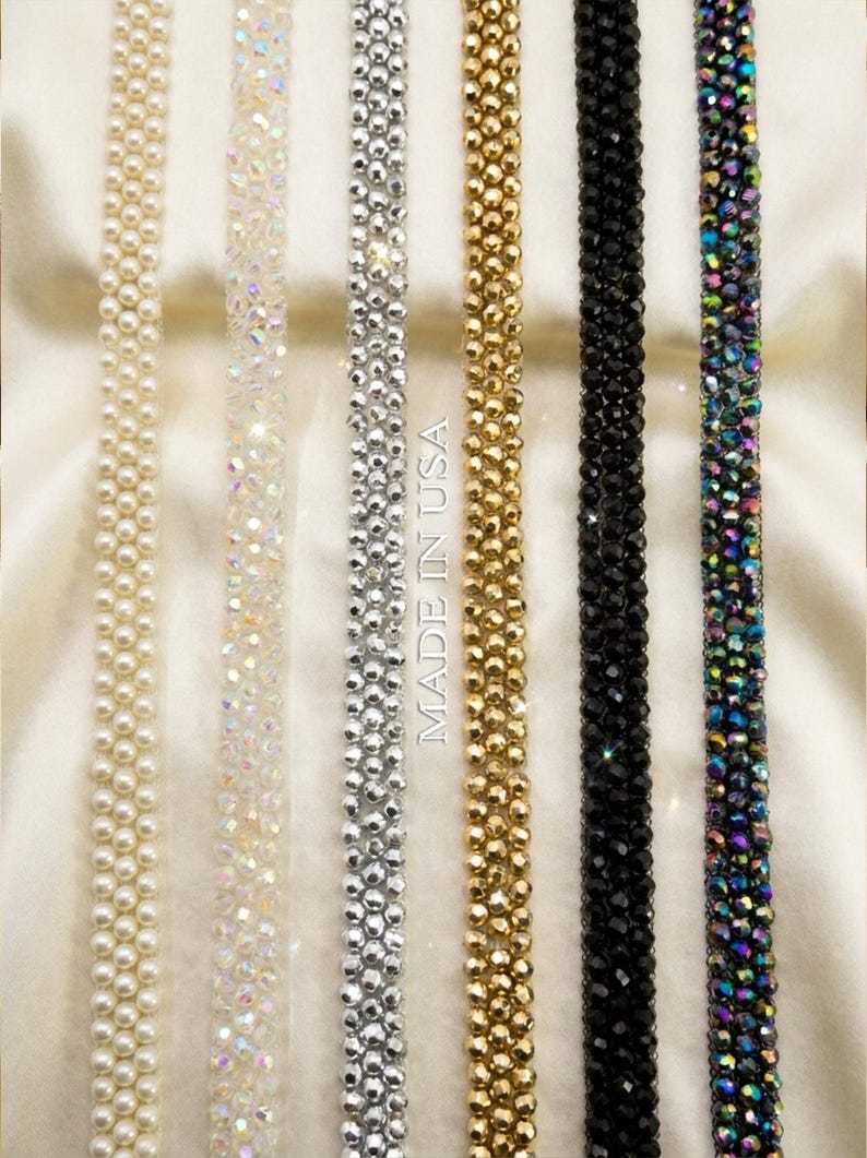 May include: Close-up of several beaded and jeweled trim strips in various colors, including cream, iridescent, silver, gold, black, and iridescent. The text "MADE IN USA" is visible. These trims are likely used for embellishing clothing or accessories.