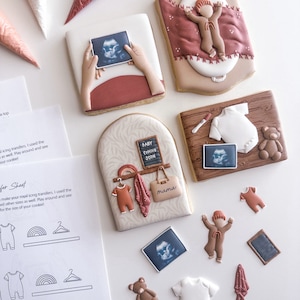 May include: A set of decorated sugar cookies with a baby theme. The cookies feature images of an ultrasound, a baby in a swaddle, a baby in a onesie, and a baby's room with a sign that says "Baby Coming Soon". There are also smaller cookies shaped like a teddy bear, a onesie, a hanger, and a baby in a hat.