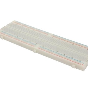 May include: A white breadboard with numerous holes for electronic components. It features red and blue lines, and is designed for prototyping circuits. The breadboard is approximately 6 inches long.