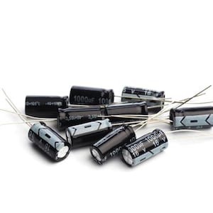 Pode incluir: Um conjunto de capacitores cilíndricos pretos com fios prateados. Cada capacitor tem texto indicando suas especificações, incluindo "1000uF 16 V". Os componentes estão dispostos sobre um fundo branco.