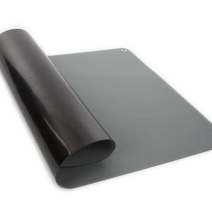 May include: A rolled-up black mat next to a flat grey mat. The grey mat has rounded corners and a small hole in the upper right corner. The background is white.
