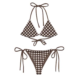 May include: A two-piece bikini set in a brown and white gingham pattern. The top is a halter style with triangle cups and ties at the neck and back. The bottoms are a tie-side style.