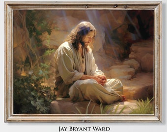 May include: A framed print of a religious figure in a serene setting. The artwork depicts a person with long hair and a light-colored robe, seated on a stone surface, with hands clasped in prayer. The frame is a light brown color. The artwork is signed by Jay Bryant Ward.