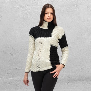 Puede incluir: Un suéter blanco y negro de patchwork con cuello alto y mangas largas.