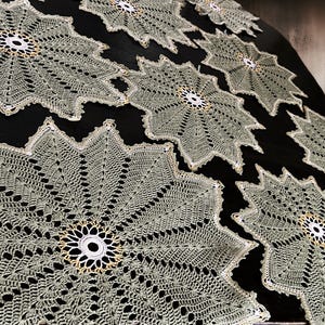 Puede incluir: Un conjunto de seis manteles individuales de ganchillo de color verde claro con un centro blanco. Los manteles individuales están dispuestos en forma circular sobre un fondo negro.