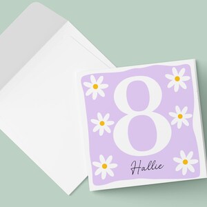 Pode incluir: Um cart&atilde;o roxo com um n&uacute;mero 8 branco e margaridas brancas com centros amarelos. O cart&atilde;o diz "Hallie" na parte inferior.