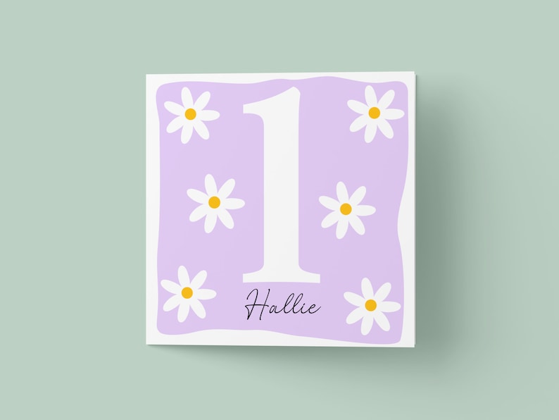 Pode incluir: Cart&atilde;o roxo com um n&uacute;mero um branco e margaridas brancas. O nome "Hallie" est&aacute; escrito abaixo do n&uacute;mero um.