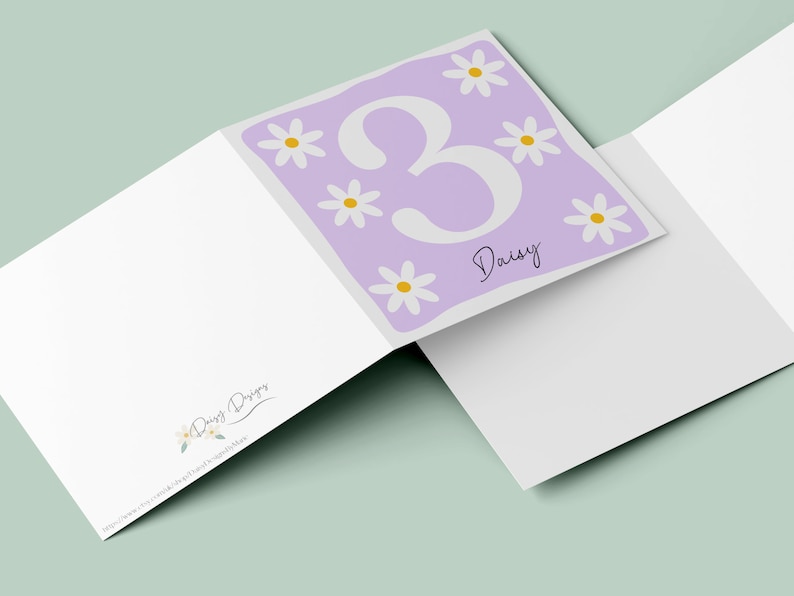 Pode incluir: Um cart&atilde;o roxo com um n&uacute;mero 3 branco e o nome Daisy escrito em it&aacute;lico. O cart&atilde;o &eacute; decorado com margaridas brancas com centros amarelos.